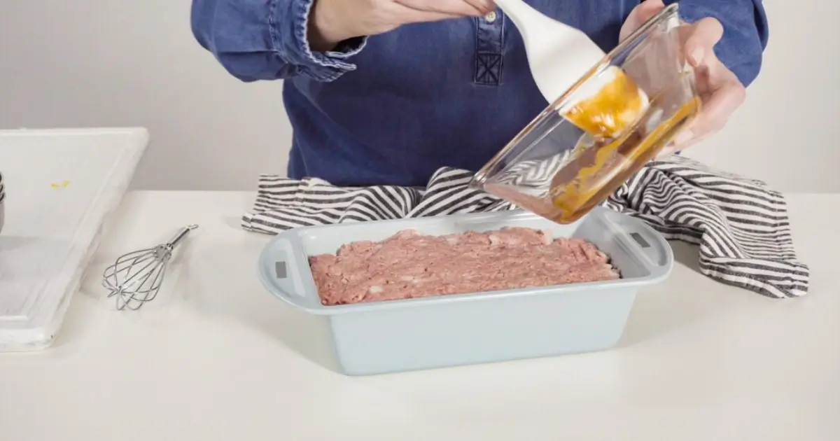 Meatloaf being glazed inside an oven with visible caramelization.